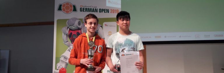 zwei Schüler mit Urkunde und Pokal