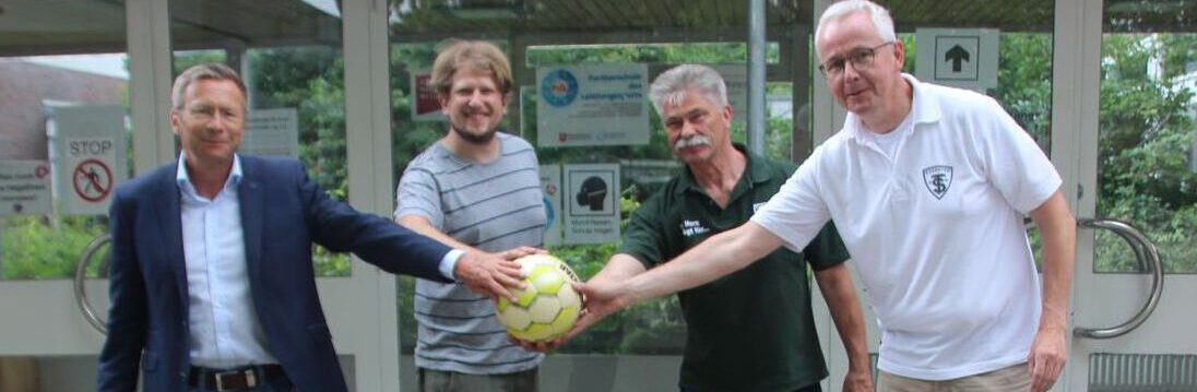 zwei Lehrer und zwei Herren vom TuS vor dem Haupteingang