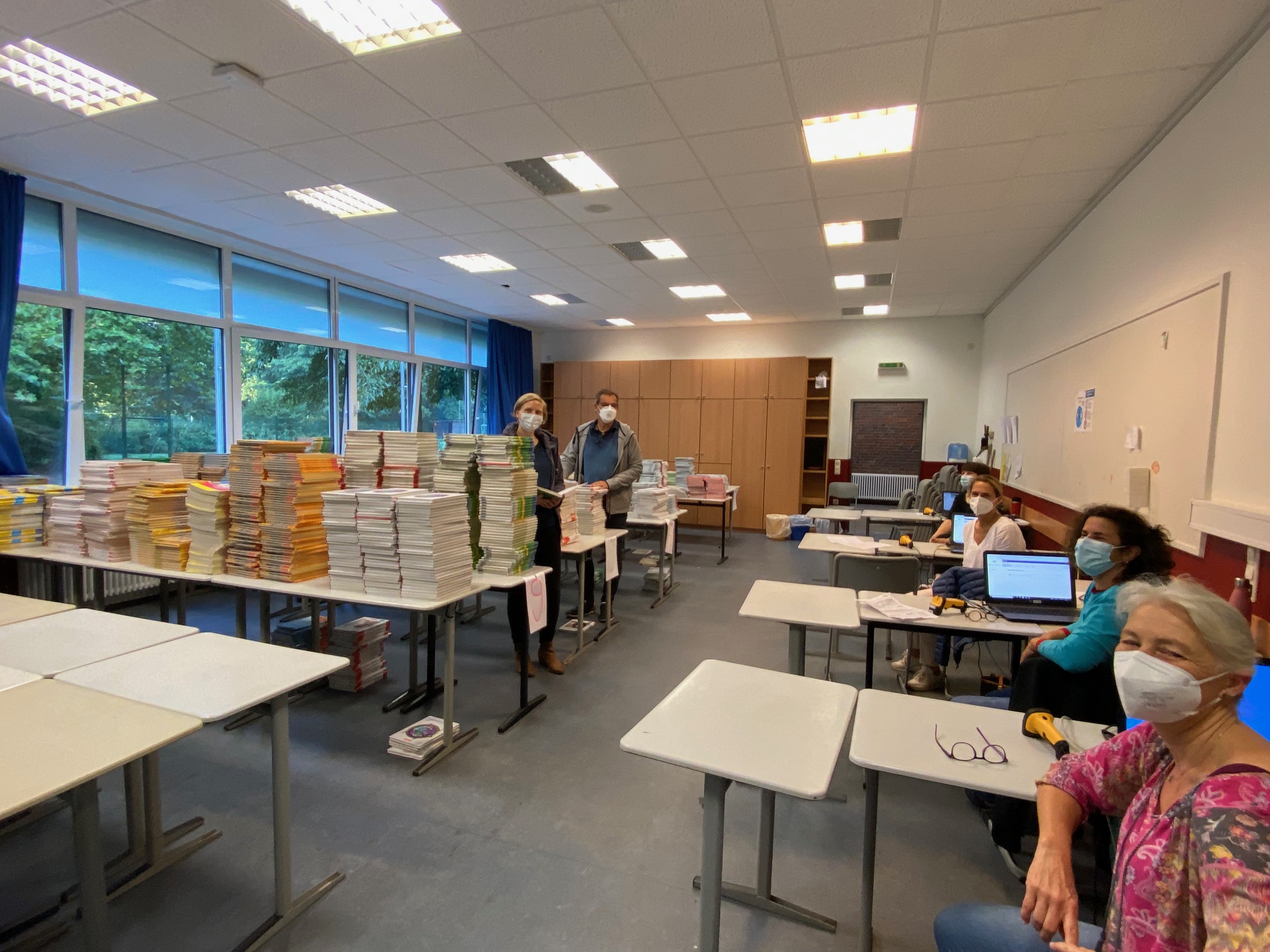 Großer Raum mit Stapeln voller Schulbücher, sechs Erwachsene