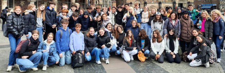 zahlreiche Schüler mit Rucksäcken lächelnd posierend