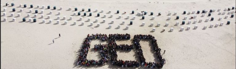 GEO-Logo von oben von Schülern gebildet am Strand