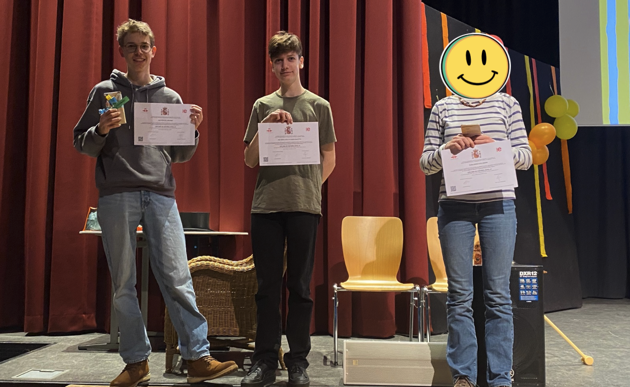 zwei Schüler und eine Schülerin auf der Bühne mit ihren Urkunden