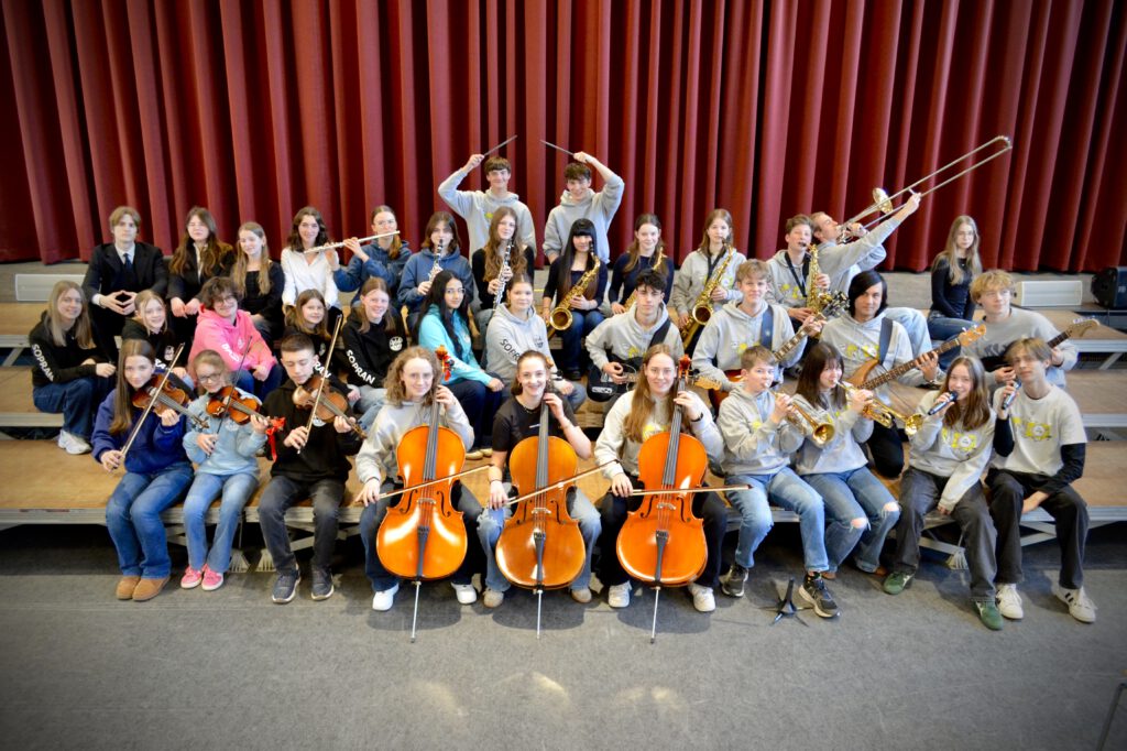 zahlreiche Schülerinnen und Schüler auf der Bühne posierend mit ihren Instrumenten