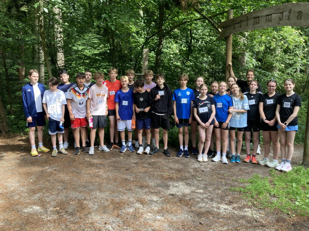 eine Klasse in bunten Sportoutfits im Wald stehend
