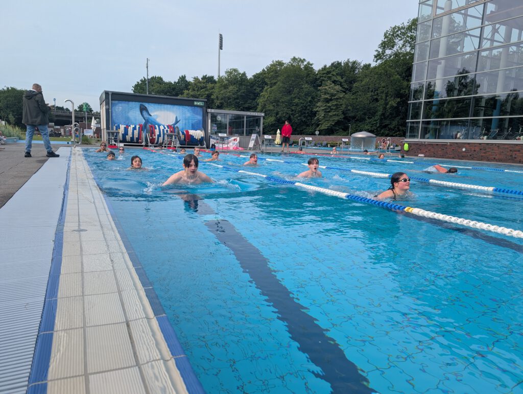 zahlreiche Schülerinnen und Schüler im Bad ihre Bahnen schwimmend